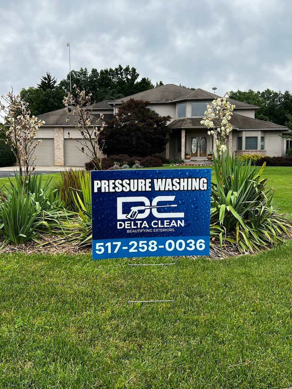 Pressure washing service sign for Delta Clean in front of a residential home. 517-258-0036.