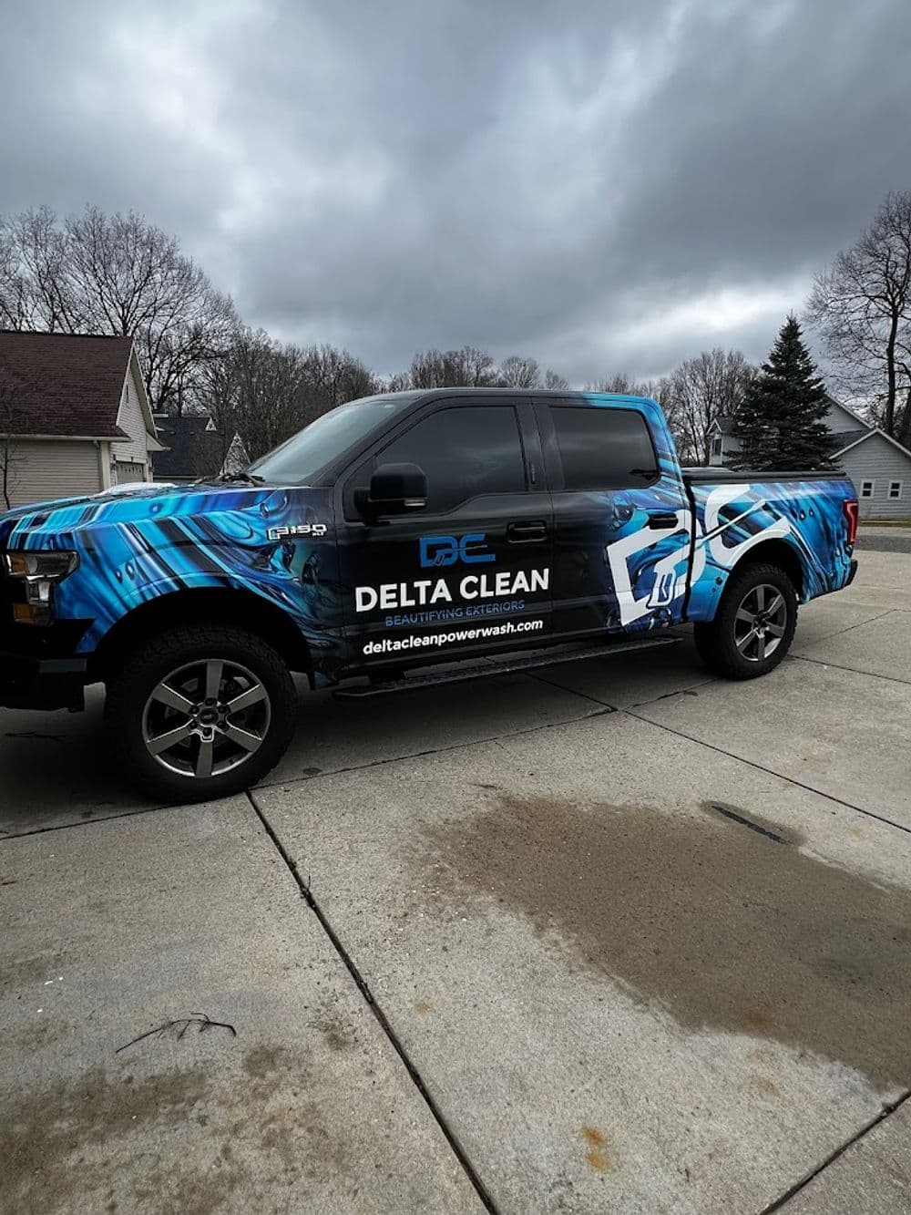 Delta Clean truck wrapped in blue design parked in residential area, showcasing branding and website.