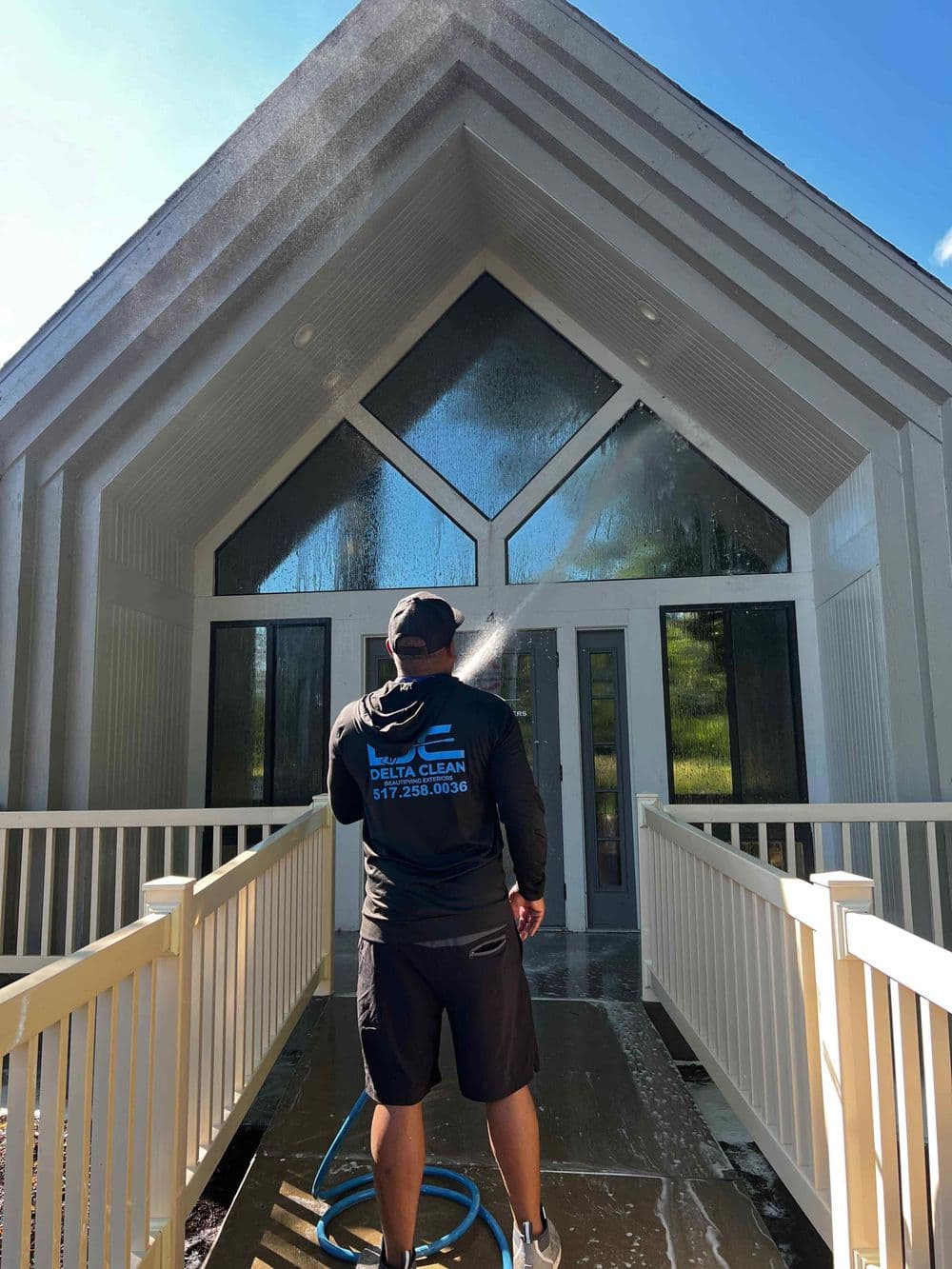 Professional pressure washing service cleaning a modern home's entrance with a hose.